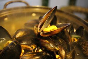 Cozze fresche pulite con una paglietta d'acciaio delicata su un piano di lavoro.