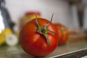 Pomodori freschi su un tavolo, evidenziando l'importanza di conservarli a temperatura ambiente.