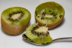 Un kiwi intero con la buccia, evidenziando la sua consistenza e colore verde brillante.